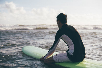 Side view of young man sitting on beach