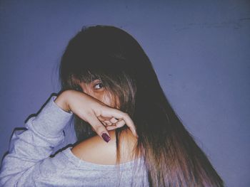 Portrait of young woman against blue wall