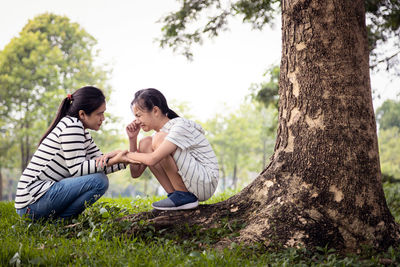 Friends sitting on tree trunk