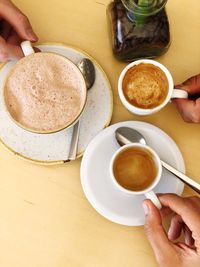 High angle view of woman holding coffee cup on table