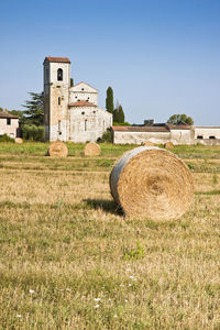 Hay bales on field against clear sky