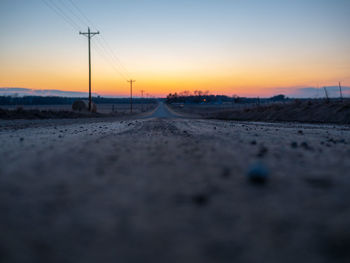 Surface level of road against sky during sunset