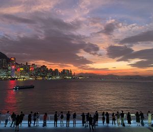 People in sea against sky during sunset