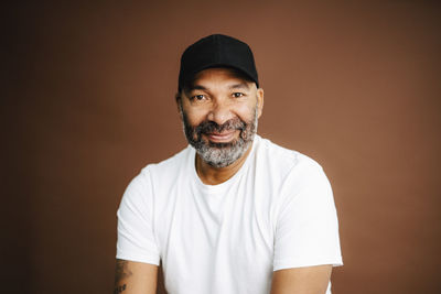 Portrait of confident man wearing hat against brown background