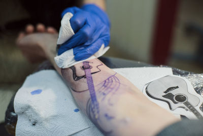 Cropped hand of artist tattooing on hand