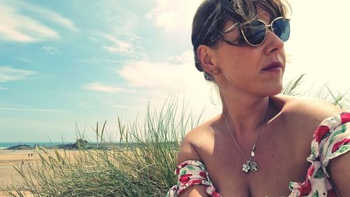 Young woman wearing sunglasses on beach against sky