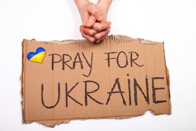 Cropped hand of woman holding text against white background