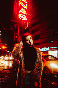 Rear view of woman standing on road at night