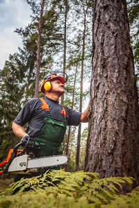 Young man sitting on tree trunk in forest