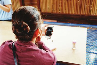 Woman using mobile phone while sitting at restaurant