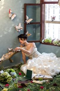 Young woman with artificial butterflies in bedroom