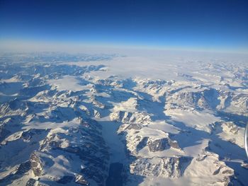 Aerial view of snowcapped mountains against blue sky