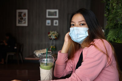 Portrait of woman wearing mask sitting at restaurant