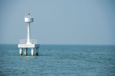 Lighthouse in sea against clear sky