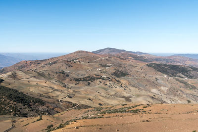 Scenic view of arid landscape against clear blue sky