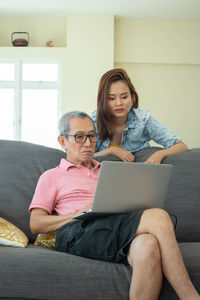 Young woman using phone while sitting on laptop