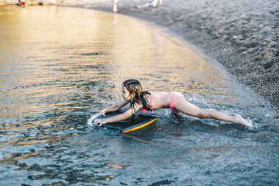 Cute girl playing with surfboard at beach