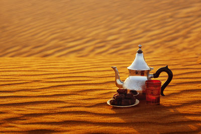 Arabian teapot, cup and dates in the desert at a beautiful sunset symbolizing ramadan