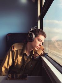 Young woman looking down while sitting on window