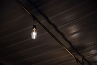 Low angle view of light bulb hanging at night