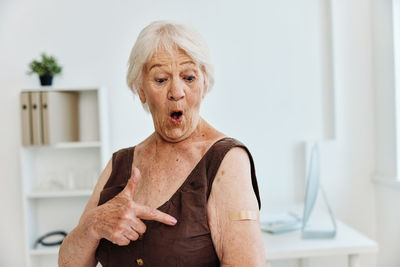 Portrait of senior woman gesturing while standing at hospital