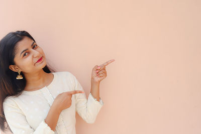 Portrait of beautiful young woman holding white wall