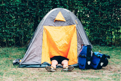 Low section of person resting in tent on field at campsite