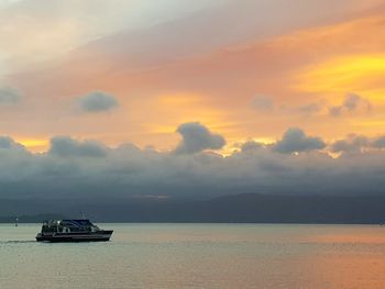 Boat sailing in sea against sky during sunset