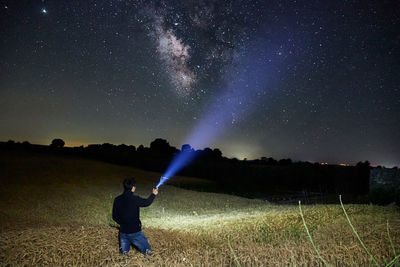 Rear view of man standing on field against sky