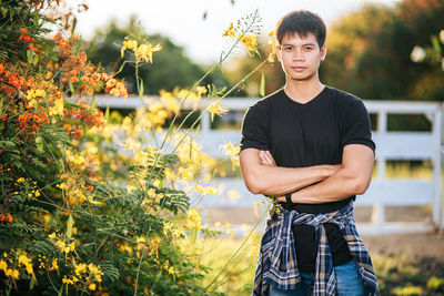 Portrait of young man standing on flowering plants