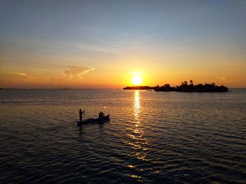 High angle view of people in rowboat on sea during sunset
