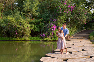 Couple standing on footbridge over lake