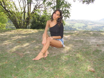 Portrait of beautiful young woman sitting on land