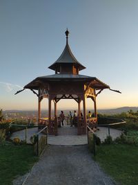 Gazebo by building against clear sky during sunset