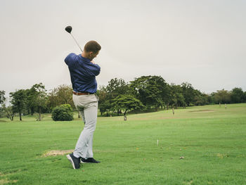 Full length of man playing golf on course against sky