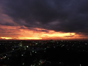 High angle view of illuminated cityscape against dramatic sky