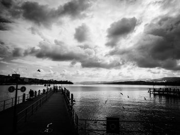 Pier on sea against cloudy sky