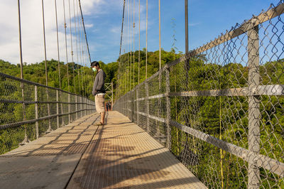 Rear view of man on footbridge against sky