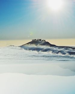 Digital composite image of people on peak in sea against sky