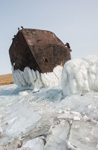 Abandoned boat at frozen beach against clear sky