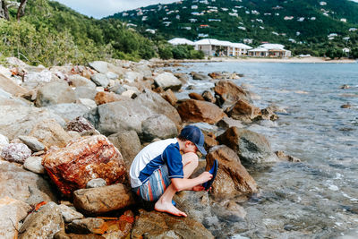 Man sitting on rock at beach