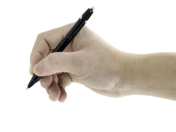 Close-up of hand holding pen against white background