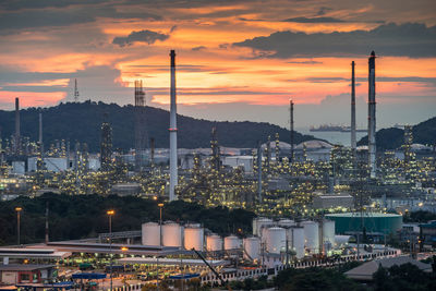 Illuminated factory against sky during sunset