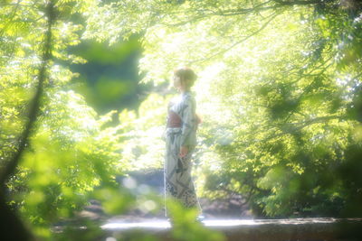 Man standing by tree in forest