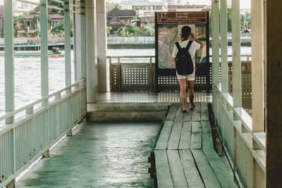 Rear view of woman standing by railing