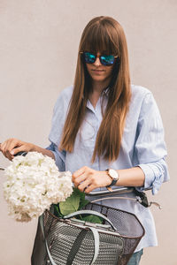 Portrait of woman with bouquet standing by bicycle