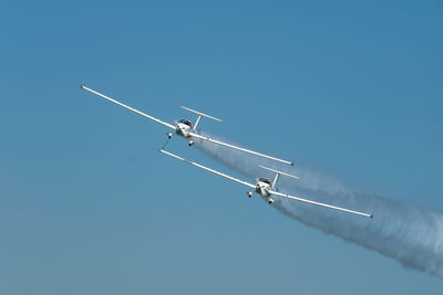 Low angle view of airplane flying against clear blue sky