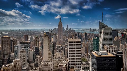 Aerial view of buildings in city against cloudy sky