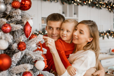 Portrait of smiling young woman holding christmas tree