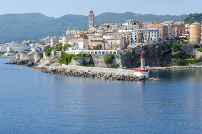 Buildings by sea against sky in city